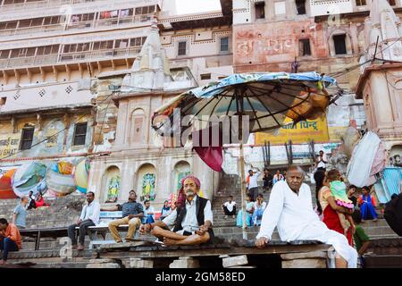 Varanasi, Uttar Pradesh, Indien : Menschen sitzen an den Ghats entlang des Ganges Flusses. Stockfoto