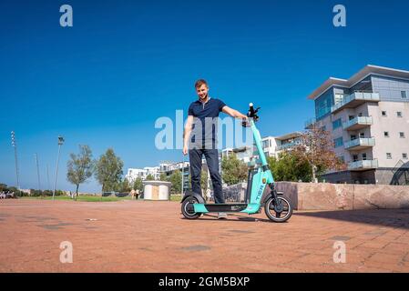 Junger Mann, der in Malmö auf einem Elektroroller durch die Straßen fährt. Stockfoto