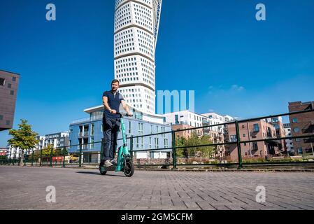 Junger Mann, der in Malmö auf einem Elektroroller durch die Straßen fährt. Stockfoto