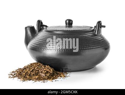 Teekannen und Stapel von trockenem grünem Hojicha-Tee auf weißem Hintergrund Stockfoto
