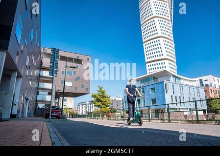 Junger Mann, der in Malmö auf einem Elektroroller durch die Straßen fährt. Stockfoto