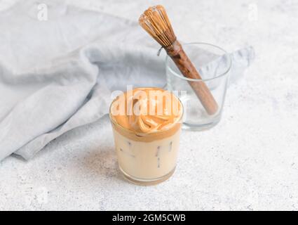 Ein Glas leckeren dalgona hojicha Latte und Chasen auf hellem Hintergrund Stockfoto