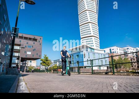 Junger Mann, der in Malmö auf einem Elektroroller durch die Straßen fährt. Stockfoto