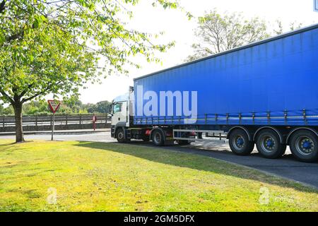 Ein Containerwagen verlässt die M27-Tankstelle Rownhams in der Nähe von Southampton England, um die Fahrt auf der Autobahn M27 zu fortsetzen. Stockfoto