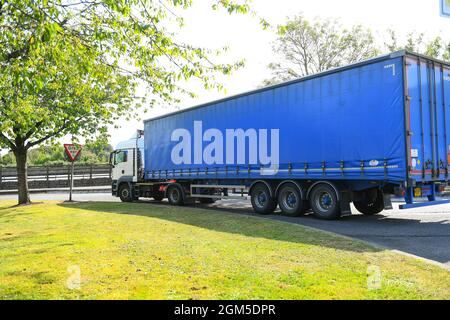 Ein Containerwagen verlässt die M27-Tankstelle Rownhams in der Nähe von Southampton England, um die Fahrt auf der Autobahn M27 zu fortsetzen. Stockfoto