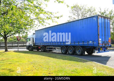 Ein Containerwagen verlässt die M27-Tankstelle Rownhams in der Nähe von Southampton England, um die Fahrt auf der Autobahn M27 zu fortsetzen. Stockfoto