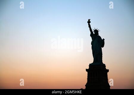 Die Silhouette von Lady Liberty während eines epischen Sonnenuntergangs im Sommer in New York City Stockfoto