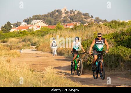 Tribunj, Kroatien - 16. August 2021: Menschen, die Fahrrad fahren und auf dem Feldweg zwischen Tribunj und Tribunj wandern Stockfoto