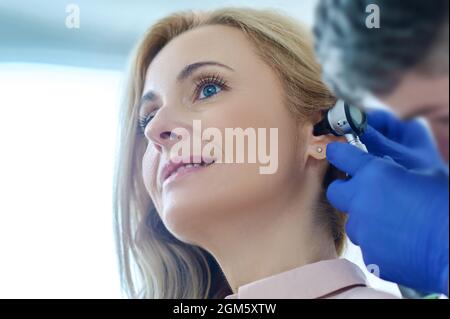 Hände in Handschuhen in der Nähe des Womans Ohr Stockfoto