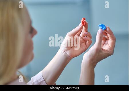 Frau, die zwei Hörgeräte in den Händen hält Stockfoto