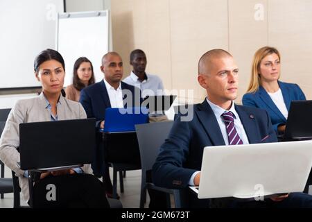 Konzentrierte Geschäftsleute, die während eines Geschäftsseminars an Laptops arbeiten Stockfoto