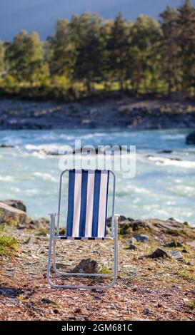 Klappstühle am Ufer eines Bergflusses an einem schönen, warmen Tag. Ein ruhiger und ruhiger Ort zum Entspannen und Nachdenken. Ausrüstung und die Erholung des Touristen. Stockfoto