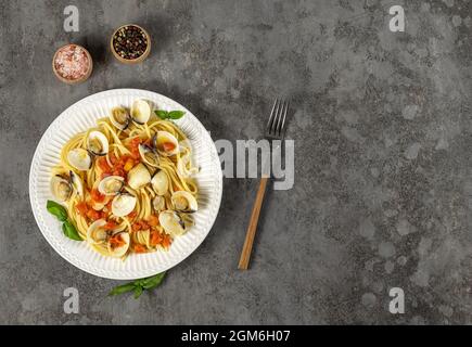 Leckere, appetitlich frische hausgemachte Venusmuscheln alle Vongole Meeresfrüchte-Pasta mit Tomaten, Knoblauch und Weißwein auf dem Teller. Draufsicht, Kopierraum. Stockfoto
