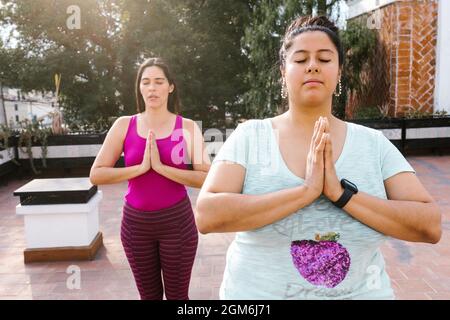 Plus size latin Mädchen meditieren mit geschlossenen Augen stehen in Outdoor-Yoga-Klasse in Lateinamerika Stockfoto