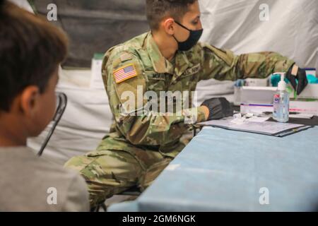 Pvt. Joseph Moran, Kampfmediziner des 528. Krankenhauszentrums, 1. Medizinische Brigade, 13. Expeditionary Sustainment Command, bereitet sich auf die Impfung eines afghanischen Kindes im Doña Ana-Komplex von Fort Bliss in New Mexico vor, 16 während er zur Unterstützung der Operation Allies Herzlich Willkommen. arbeitete 2021 Das Verteidigungsministerium stellt über das Northern Command der USA und zur Unterstützung des Heimatschutzministeriums so schnell wie möglich Transport, vorübergehende Unterbringung, medizinische Vorsorgeuntersuchungen und allgemeine Unterstützung für mindestens 50,000 afghanische Evakuierte in geeigneten Einrichtungen, in permanenten oder temporären Strukturen bereit. Th Stockfoto