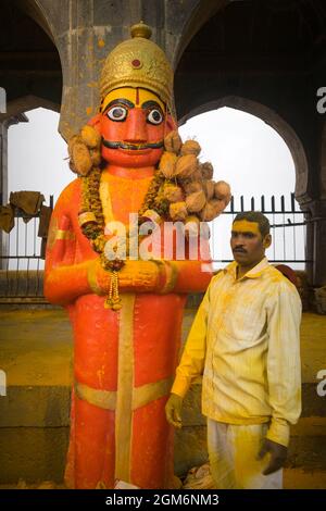 Ein Mann, der in der Nähe einer Statue von Lord Khandoba vor dem berühmten und schönen Khandoba Tempel in Jejuri während des Festivals von Somvati Amavasya steht Stockfoto