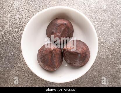 Drei köstliche Schokoladentrüffel auf Keramikgeschirr, Nahaufnahme, auf einem Metalltablett, Draufsicht. Stockfoto