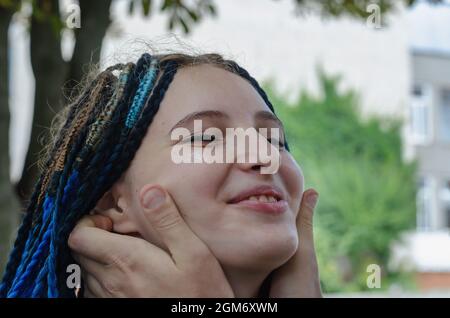 Porträt einer glücklichen jungen erwachsenen Frau mit langen blauen Zöpfen. M Stockfoto