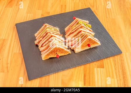 club-Sandwich-Spieße mit Schichten aus Hühnerfilet, Schinken und Käse in Tranchetten, Salat und Tomaten, Mayonnaise und Senf Stockfoto