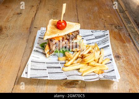 Roastbeef-Sandwich mit Rucola, Kirschtomate, geschmolzenem Cheddar und Pommes frites Stockfoto