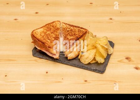 Gemischtes Sandwich mit Schinken und geschmolzenem Käse, gegrilltem Brot mit Butter und garniert mit Pommes frites Stockfoto