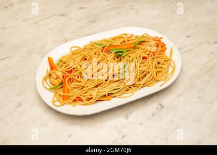 Sautierte Spaghetti mit Gemüse und Garnelen im orientalischen Stil auf weißem Tablett Stockfoto