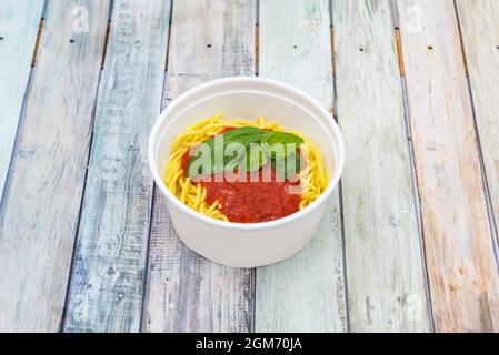 Home Service Schüssel mit Spaghetti Rezept mit Pomodoro-Sauce und Basilikum auf Holztisch Stockfoto