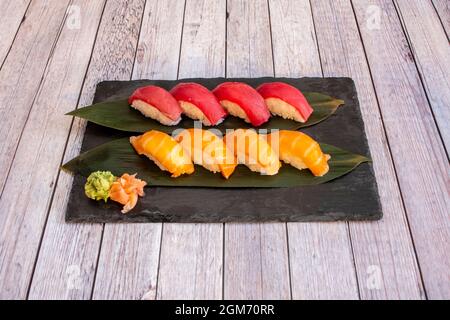 Großartiges Tablett mit Nigiri-Sushi mit vier Stücken norwegischen Lachs und vier Stücken mediterranem roten Thunfisch auf Bananenblättern mit Wasabi und Ginseng Stockfoto