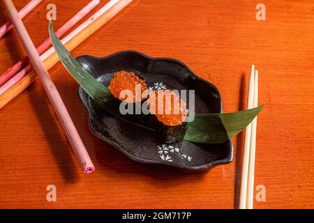 Norwegisches Lachs-Rogen-Gunkan-Sushi, Nori-Algenboot auf Bananenblatt Stockfoto