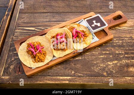 Dreiteilige Portion der beliebten mexikanischen Cochinita pibil Taco mit lila Zwiebeln und Chipotle-Sauce in einer weißen Schüssel Stockfoto