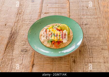 Typisch mexikanischer Pastor Taco mit Kalk- und Maistortilla auf grünem Teller Stockfoto