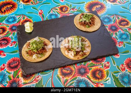 Weizenmehl-Tacos mit Rinderbirria, viel gehacktem Koriander, weißen Zwiebeln und Limettenkeilen Stockfoto