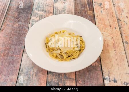 Teller mit Tagliatelle mit Trüffel und gebratenen Parmesan-Käse-Flocken auf Holztisch Stockfoto