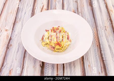 Italienische Tagliatelle Carbonara Rezept mit Trüffel auf weißen tiefen Teller und Vintage-Tisch Stockfoto