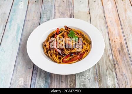 Sautierte Nudeln mit viel Rinderfilet, viel Tomaten und Paprika, rote Zwiebel und gehacktem Schnittlauch, alles nach peruanischem Rezept mit s gekocht Stockfoto