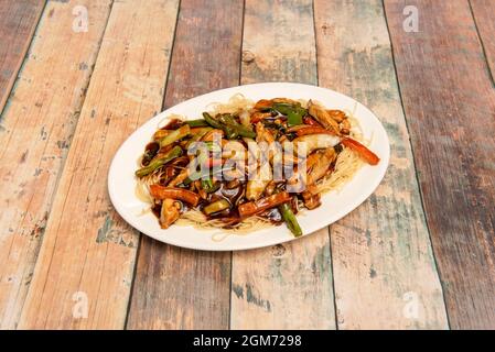 Gebratene Nudeln mit Gemüse und Huhn mit viel Sojasauce, die in einem chinesischen Fast-Food-Restaurant zubereitet werden Stockfoto