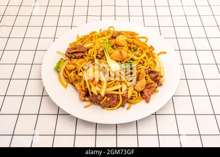 Drei Köstlichkeiten Tagliatelle mit Rind, Huhn, Salat und Zwiebel auf einer weißen Tischdecke mit schwarzen Streifen Stockfoto