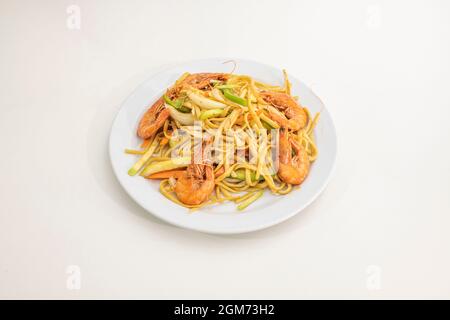 Gebratene Nudeln mit grünen Paprika, Zucchini, Karotten und weißen Zwiebeln mit gegrillten, gebratenen Garnelen, die in einem chinesischen Restaurant zubereitet werden Stockfoto