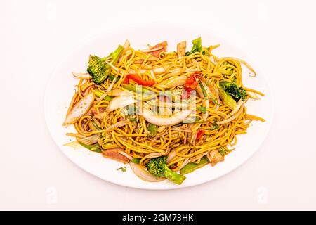 Teller mit sautierten Nudeln mit Brokkoli, Zwiebeln, roten Paprika und Rindfleisch mit Sojasauce auf dem Teller und weißem Hintergrund Stockfoto