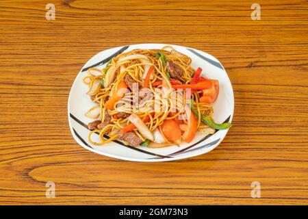 Peruanisches Rezept aus sautierten Nudeln mit Rinderfilet, gewürfelten Tomaten und Zwiebeln, Streifen roter und grüner Paprika und Sojasauce Stockfoto