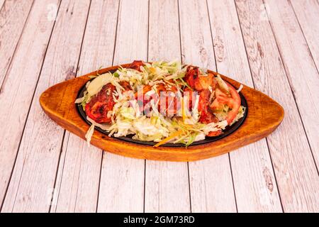 Tolles indisches Essenstablett mit Tandoori-Hühnchen-Rezept mit Eisbergsalat auf einem Holztisch Stockfoto