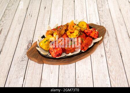 tandoori-Hähnchenspießtablett mit Garnelen und einem Bett mit weißen Zwiebeln Stockfoto