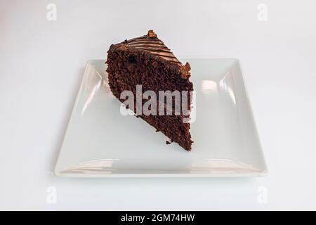 Portion Brownie mit zwei Lagen Shortbread und glänzendem Zuckerguss auf einem quadratischen weißen Porzellanteller Stockfoto