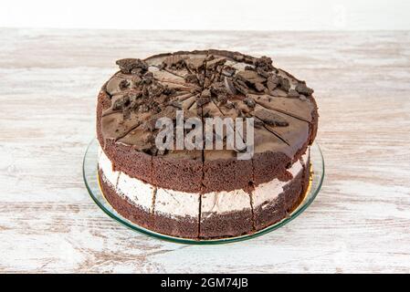 Schokoladenkuchen mit gehackten Keksen auf Holztisch Stockfoto