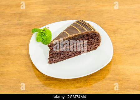 Portion köstlicher Schokoladenkuchen mit drei Schichten Biskuitkuchen mit glänzender Schokoladenbeschichtung Stockfoto