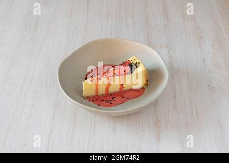Käsekuchen mit Erdbeer- und Mohn-Smoothie auf hellem Holztisch Stockfoto