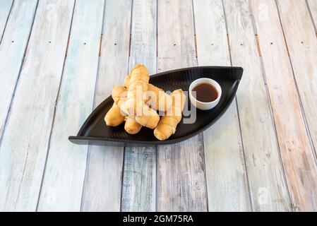 Portion venezolanischer tequeños mit Zuckerrohrsirup auf einem schwarzen Tablett Stockfoto