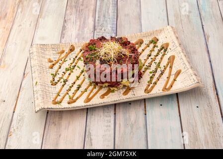 Rote Beete-Tartare mit Bohnensprossen, gehackter Petersilie und Schnittlauch und Mohnsamen auf beigem Teller Stockfoto