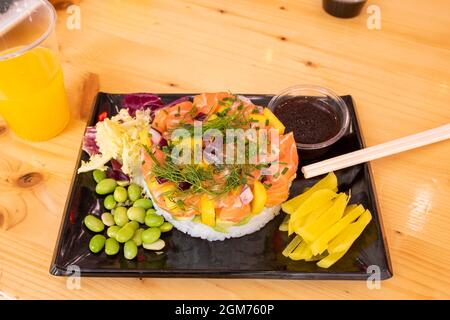 Großartige Lachsschartar mit Zutaten aus einer Poke-Schüssel, frischen Dillzweigen, edamamen Bohnen, gehacktem Pfeffer und gehackter Mango, roter Zwiebel und weißem Reis Stockfoto