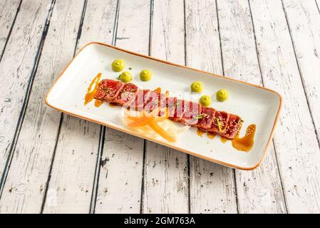 Rotes Thunfisch-Tataki-Rezept mit Sojasauce, pflanzlichem Filigran und Anklängen von Schnittlauch und Samen Stockfoto